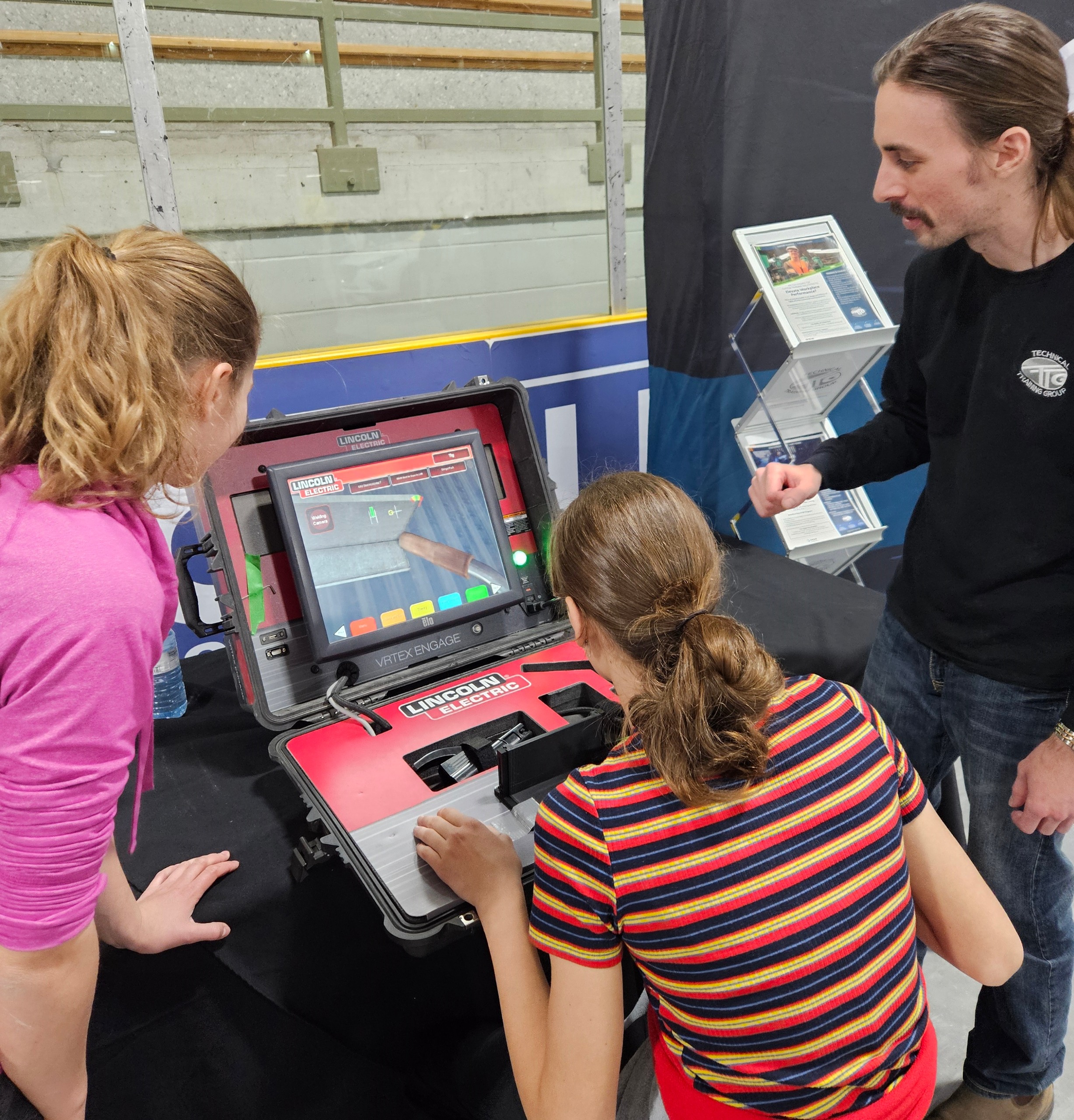 Two youth using the virtual welding simulator with an instructor beside them.